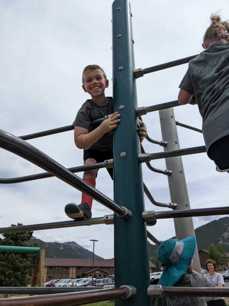 Kyle smiles big as he climbs on the playground.