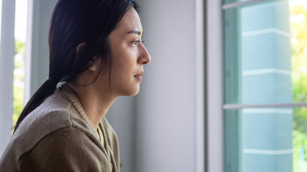 Woman staring out of window with serious expression