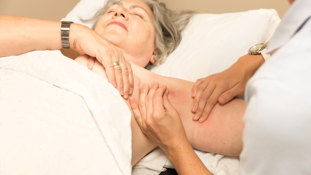 An older female patient is having a medical professional massage the upper arm.